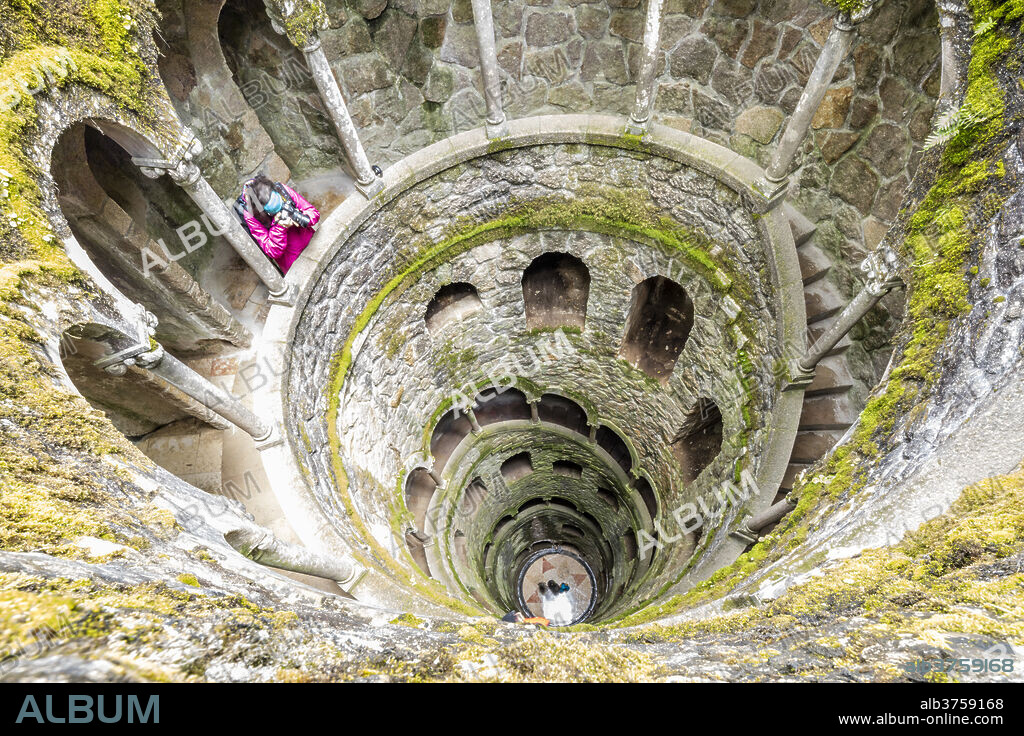 Photographer at the top of the spiral stairs inside the towers of Initiation Well at Quinta da Regaleira, Sintra, Portugal, Europe.