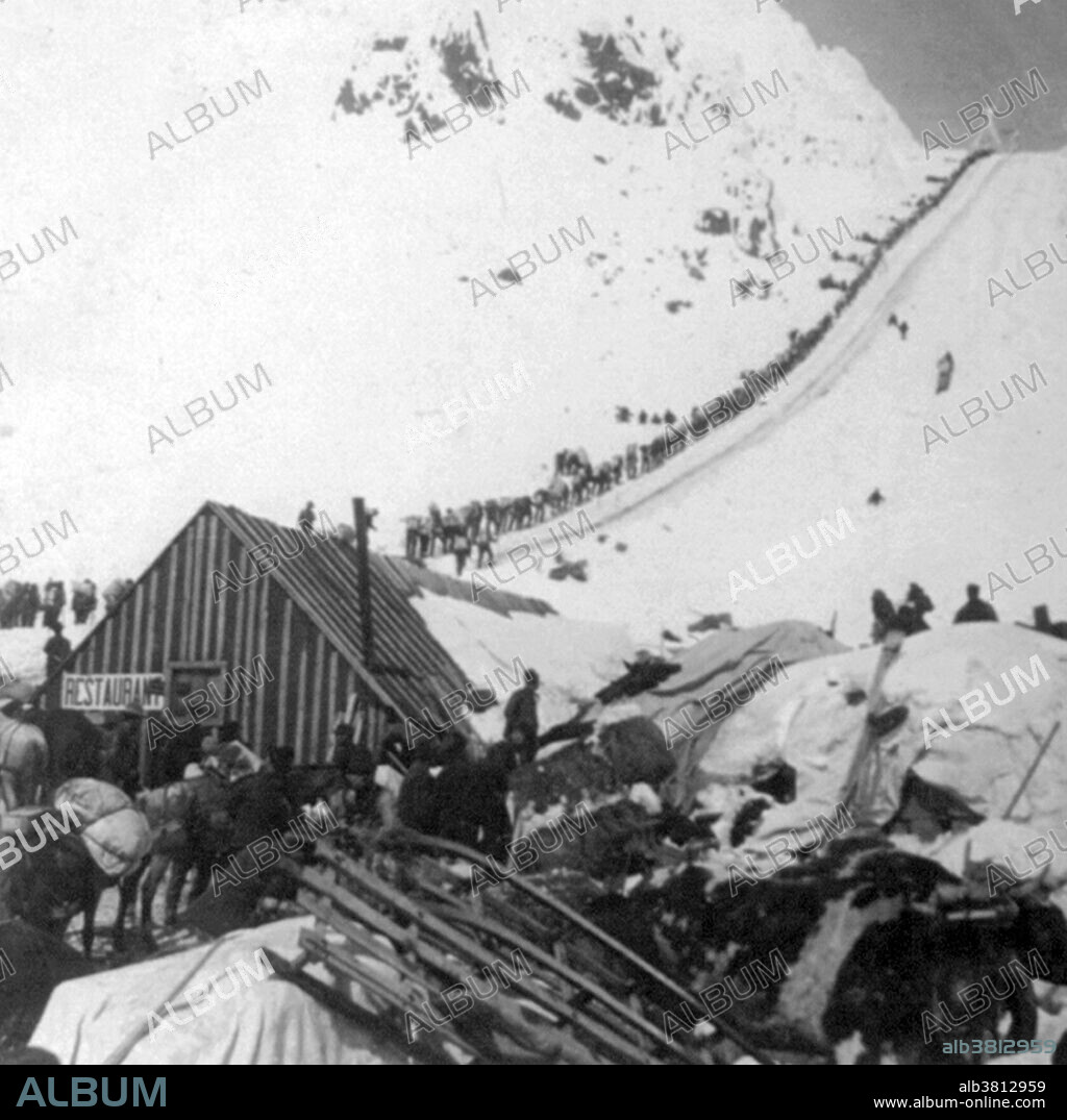 Bound for the Klondike Gold Fields, Chilcoot Pass, Alaska. The Klondike Gold Rush was a migration by an estimated 100,000 prospectors to the Klondike region of the Yukon between 1896-99. Gold was discovered by local miners on August 16, 1896 and, when news reached Seattle and San Francisco, it triggered a stampede of would-be prospectors. To reach the gold fields most took the route through the ports of Dyea and Skagway in Alaska. Here, the Klondikers could follow either the Chilkoot or the White Pass trails to the Yukon River and sail down to the Klondike. Each of them was required to bring a year's supply of food by the Canadian authorities in order to prevent starvation. In all, their equipment weighed close to a ton, which for most had to be carried in stages by themselves. Together with mountainous terrain and cold climate this meant that those who persisted did not arrive until summer 1898. Mining was challenging as the ore was distributed in an uneven manner and digging was made slow by permafrost. In the summer of 1899, gold was discovered around Nome in west Alaska, and many prospectors left the Klondike for the new goldfields, marking the end of the rush. Gold mining activity lasted until 1903. Cropped stereograph card, Keystone View Company, 1898.