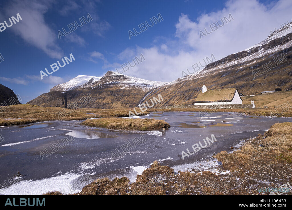 Spectacular mountain scenery surrounding Saksun and pretty turf roofed church, Streymoy, Faroe Islands, Denmark, Europe.