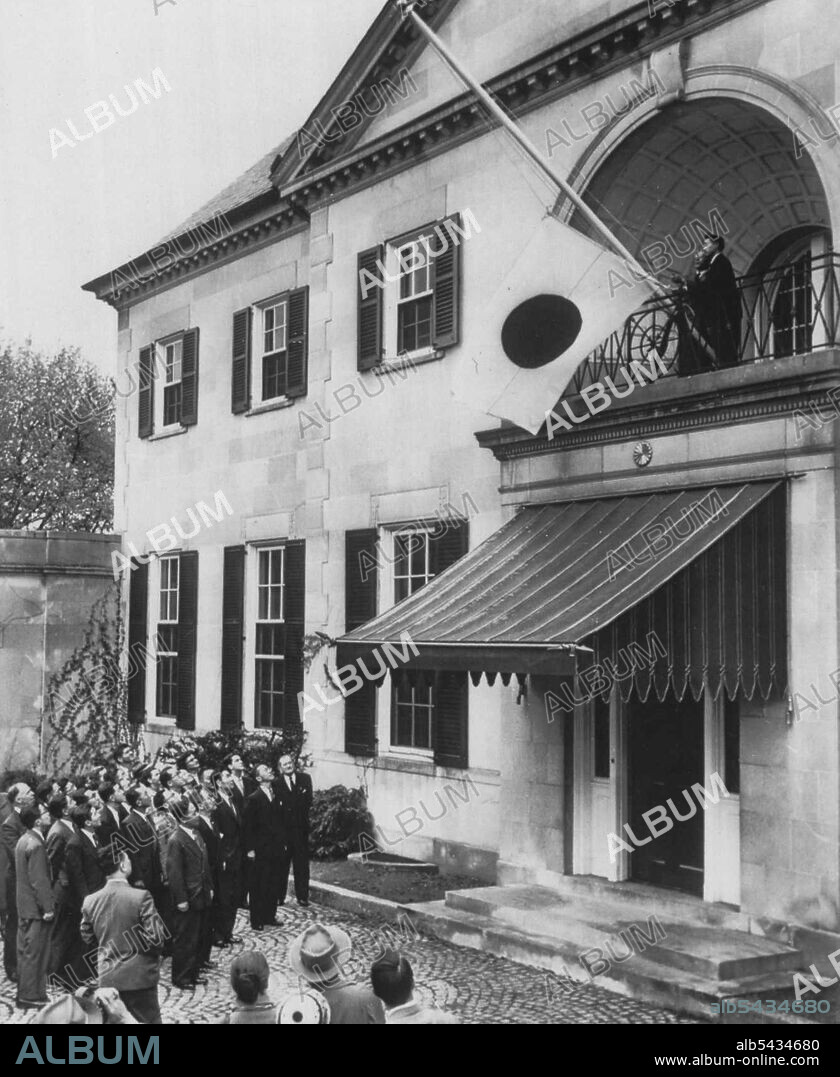 Japanese Raise Flag At Embassy -- The rising sun flag of Japan is raised at the Japanese Embassy today in a ceremony at the front entrance to the building on Massachusetts Avenue's "Embassy Row." Raising the flag are Akira Nakazawa and Kiyoshi Sumiya (right) of the embassy staff. Embassy personnel stand at lower left to watch the flag raising. April 28, 1952. (Photo by AP Wirephoto).