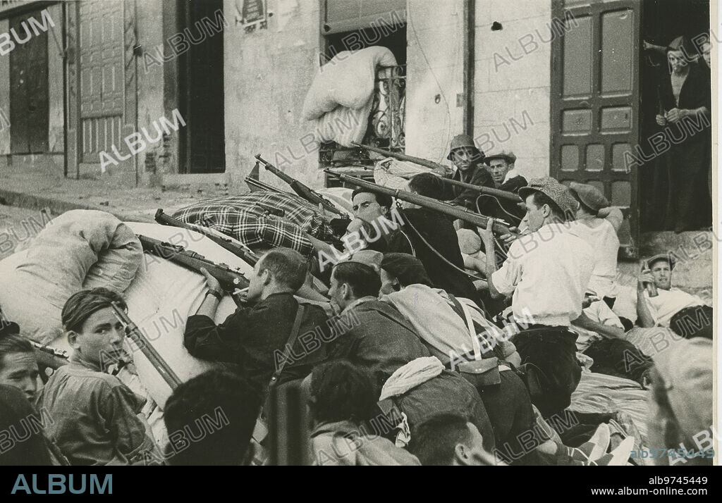 Toledo (España), 1936. Guerra Civil Española. Una gran barricada de una de las calles toledanas hace un intenso fuego contra la Academia Militar de Toledo.