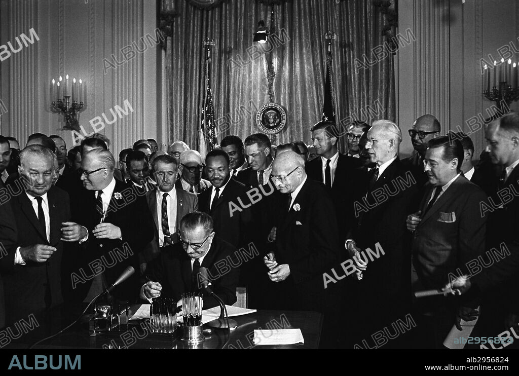 Photograph of Lyndon Johnson, President of the United States of America, signing Civil Rights Act. Behind Johnson is Martin Luther King Jnr. Dated 1964.