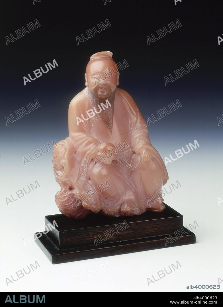 Soapstone figure of Dongfang Shuo, China, c1630-c1680. Pink soapstone seated smiling figure, late Ming-early Qing dynasty, of Dongfang Shuo with one hand holding a peach, a symbol of longevity in China. According to Chinese legend, Dongfang Shuo stole and ate some magical peaches which endowed him with magical powers and caused him to live to be 800 years old. The face, beard and borders of the robes are intricately incised. The signature of Yang Yuxuan is subtly incised on the rock seat. Yang Yuxuan was a native of Zhangp'u, Fujian Province, but resided in the provincial capital, Fuzhou. The District Gazetteer of the Zhangpu area compiled in the Kangxi period described him as 'a capable carver of Shoushan stone (soapstone), all his figures, birds and animals and his vessels are exquisite in the extreme'. Recent research has discovered that Yang began work at some time in the late Ming dynasty and worked into the Kangxi period.