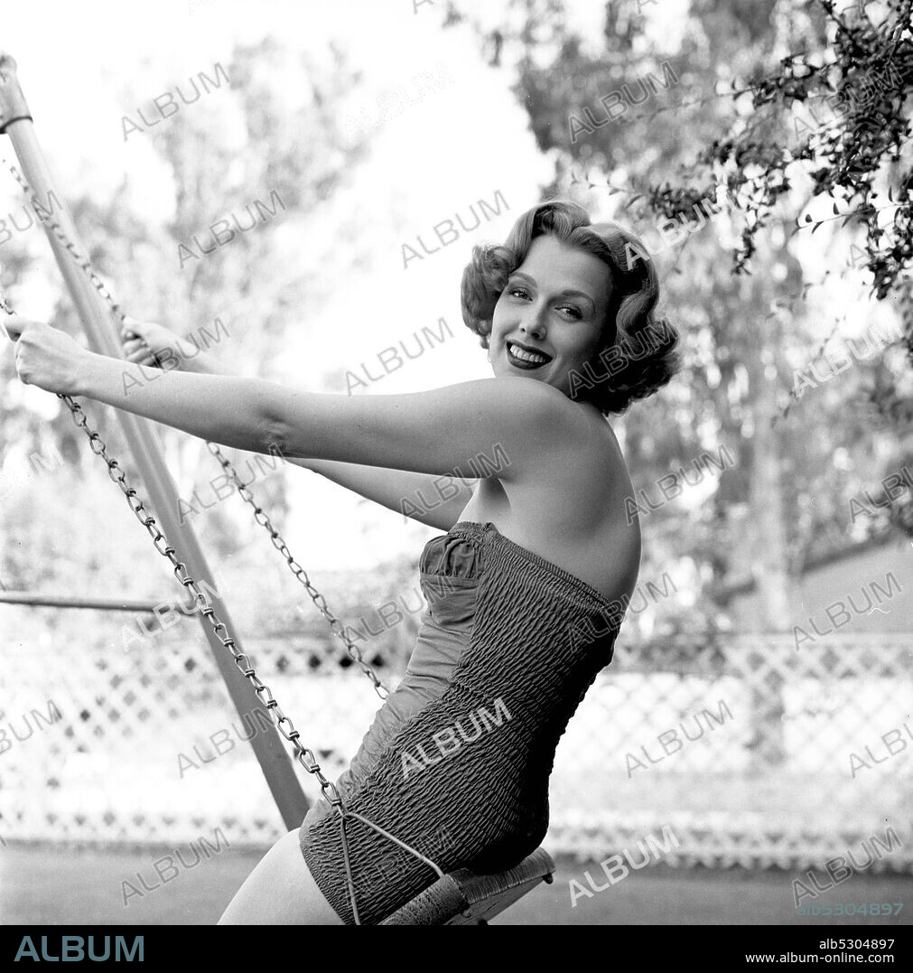 NOREEN NASH. Circa 1950, Hollywood, California, USA: 1940's American actress and model NOREEN NASH on a swing in the garden.