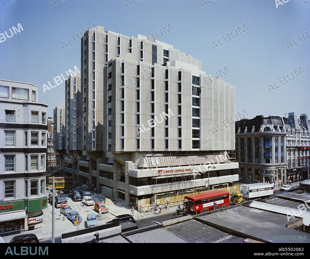 JOHN LAING PLC. An elevated view of the Central London YMCA from the north-west, with scaffolding and hoardings around the lower storey of the west facade of the podium. It was announced in February 1971 that Laing had started work on a new building at Central London YMCA, to replace an existing building which had opened in the 1910s. The project comprised four residential towers between 6 and 12 storeys high, above a podium. The towers would accommodate 1,200 residents in over 700 single and double bedrooms; staff would be accommodated in penthouse suits on the top of the three lower towers. The towers were built on a two-storey podium containing restaurants, offices, a public library, and shops. Beneath the buildings were basements 16 metres below street level, for car parks, a swimming pool, a gymnasium, a sports hall, and a conference centre. The basements and podium, which were built using reinforced concrete and structural steel, comprised Phase I of the project. The towers were built in Phase II. They were clad in 2,000 precast concrete panels and used deeply moulded white concrete window panels, both manufactured by John Laing Concrete in Princes Risborough. The building was completed in 1977, though it was partially occupied by October 1976.
