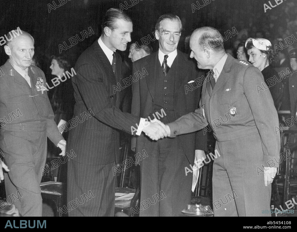 Duke At El Alamein Reunion London: Field Marshal Viscount Montgomery of El Alamein (left) watches as the Duke of Edinburgh shakes hands with General Grienther (right), supreme Allied Commander in Europe, during the 1953 El Alamein reunion, held at the Empress Hall, Earl's Court. Also looking on is Foreign Minister Anthony Eden (second from right), who was the principal speaker. The remain is held annually for men of Montgomery's famed 8th Army the "Desert Rats.". October 23, 1953. (Photo by Herbert Ludford, United Press Photo).