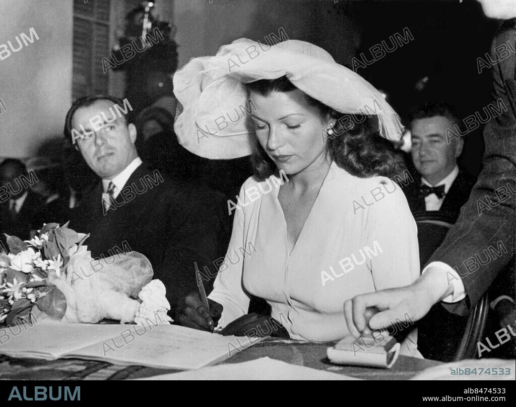 Orig. bildtext... RITA HAYWORTH WEDS PRINCE ALY KHAN IN VILLAGE HALL FLOWN BY SPECIAL PLANE FROM CANNES In the little village of Vallauris, near Cannes,today, Hollywood film actress, Rita Hayworth was married to Prince Aly Khan, son of the Aga Khan. The wedding, most talked of of the year, was planned to be held at the Chateau de l'Horizon, but was performed in a small room in the village hall by the Communist Mayor of Vallauris, M. Paul Derignan, who refused to officiate at the Chateau. PHOTO SHOWS: RITA HAYWORTH signs the register after the ceremony. Anm. Hayworth, Rita, 1918-87, amerikansk skådespelerska Registrering Formaliteter Brudbuketter Läskpressar Filmstjärnor Brudar CD172 persons: RITA HAYWORTH sites: FRANKRIKE;VALLAURIS;USA*.