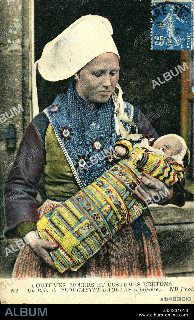 Bretonne bercant son bebe lange avec des langes brodes. Plougastel-Daoulas, Finistere. Carte Postale colorisee fin 19eme 1900. Credit GROB/KHARBINE TAPABOR.