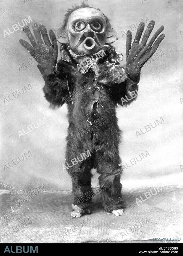 Edward S. Curits Native American Indians - Koskimo person wearing oversized gloves and mask of Hami ('dangerous thing') during the numhlim ceremony circa 1914.