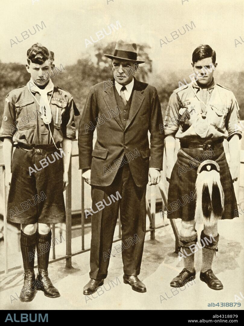 Ernest Shackleton with James Marr and Norman Mooney, 1921, (1935). British explorer Shackleton (1874-1922) with boy scouts 'Marr and Mooney, specially chosen to accompany the expedition'. On 17 September 1921 the Shackleton-Rowett Expedition left England on the 'Quest', its purpose to circumnavigate the Antarctic continent. The expedition reached Madeira the following month where Mooney was put ashore due to seasickness. Shackleton died on 5 January 1922. From "The Silver Jubilee Book - The Story of 25 Eventful Years in Pictures". [Odhams Press Ltd., London, 1935].