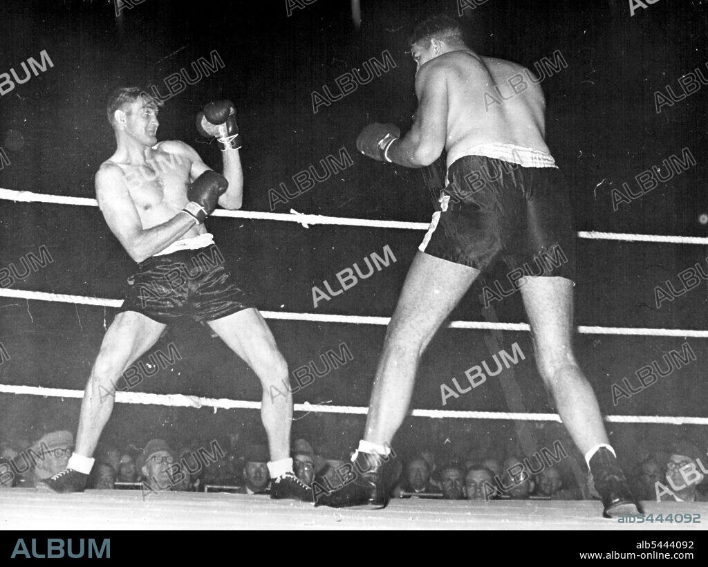 Ewart Potgieter (right) towers over 6ft 2in Fred McCoy as he bears down on him in their Durban fight. Making his ring debut, Potgieter, weighing 318¼lb an standing 7ft 2in high, sent McCoy out of the ring for the full count within 30 seconds of the opening bell. Potgieter dwarfs his 13st 21b opponent Fred McCoy as he advances to launch a 30-second knockout attack. December 01, 1954.