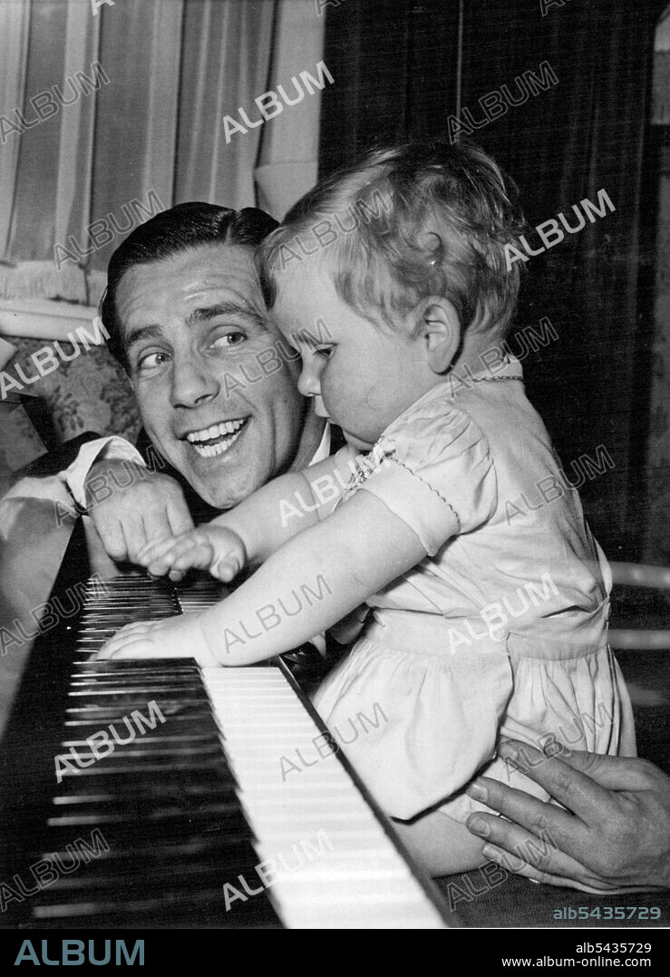 Comedian Norman Wisdom, of London, and his 15-month-old son, Nicholas, are the life and soul of any party they attend. Norman usually sings few songs while his son has a thumping good time on the piano, accompanying him. July 21, 1954. (Photo by Daily Mirror).