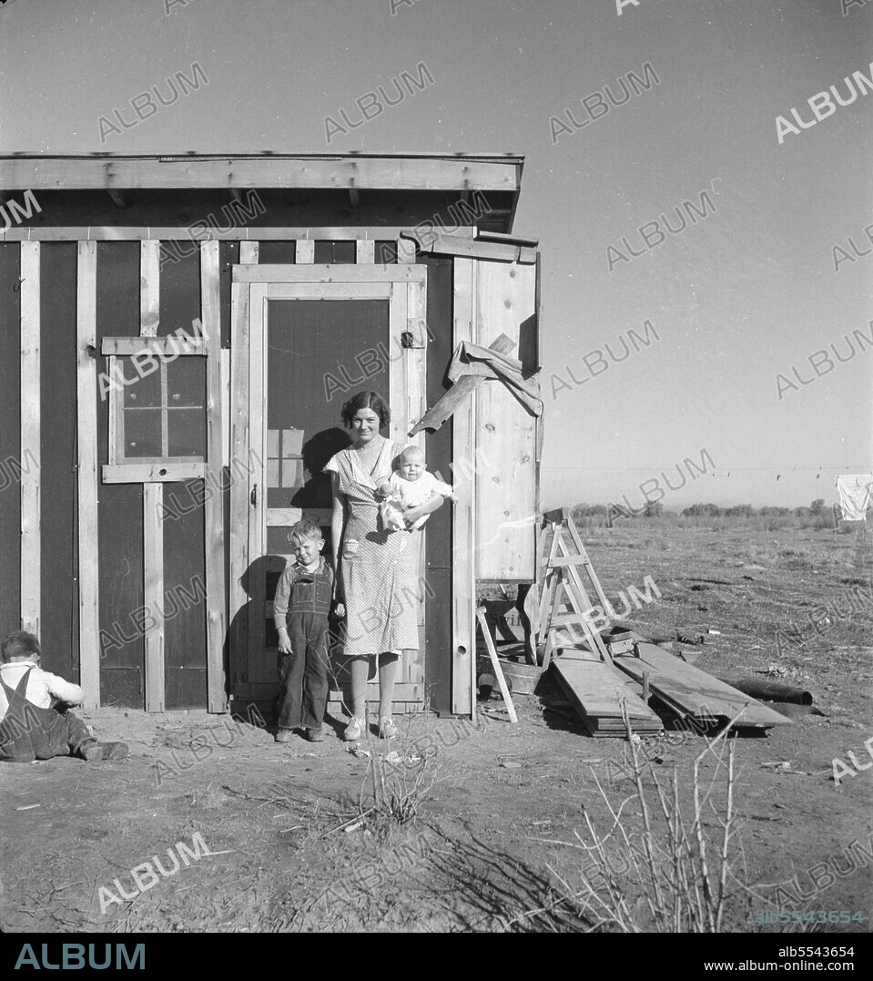 DOROTHEA LANGE. Resettled at Bosque Farms project. Family of four from Taos Junction shows temporary dwelling.