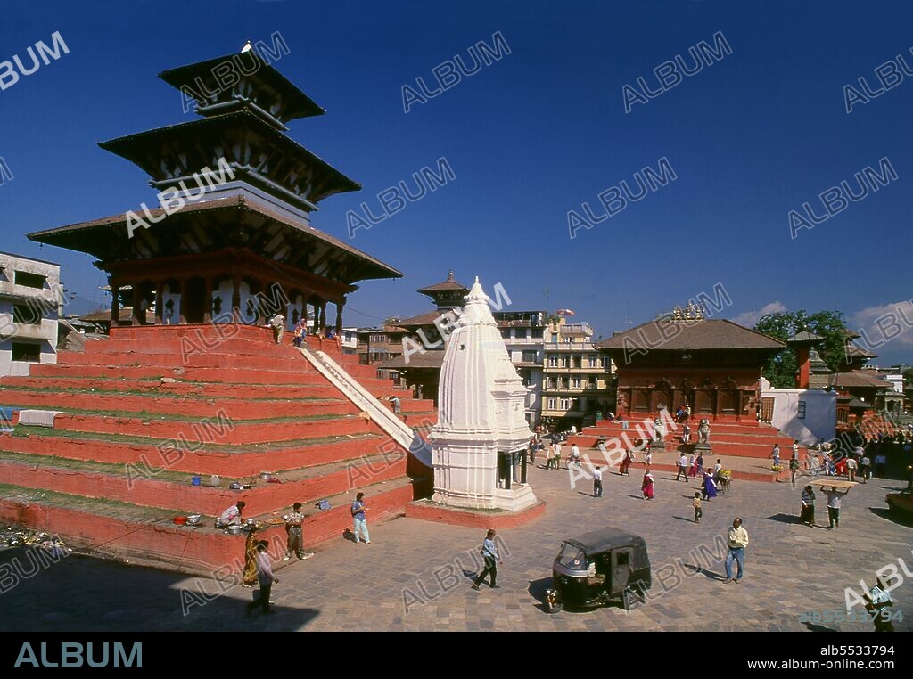 Encompassing a former royal palace, a wealth of temples and many other monuments, Durbar Square is Kathmandu’s historic and spiritual centre. The square, after years of neglect, was renovated in 1972-75 in the Hanuman Dhoka Project, initiated after the ascension to the throne of King Birendra. 'Durbar', or correctly <i>darbar</i>, means royal palace or royal court, but the locals prefer to call the square Hanuman Dhoka, 'Hanuman’s Gate', after the narrow palace gate which is guarded by a crimson-red figure of the monkey god Hanuman. The figure was set up in 1862 to protect the gate from ill luck and enemies of all sorts—or, as the Nepalese chronicles put it, from 'evil spirits, witches, and epidemics, such as smallpox'. Hanuman is worshipped mainly on account of his bravery and strength, and has often been adopted by Hindu soldiers as their patron deity. In times gone by, fortresses were guarded by images of Hanuman hewn into their walls, and the kings of Kathmandu and Bhaktapur displayed Hanuman figures on their banners.