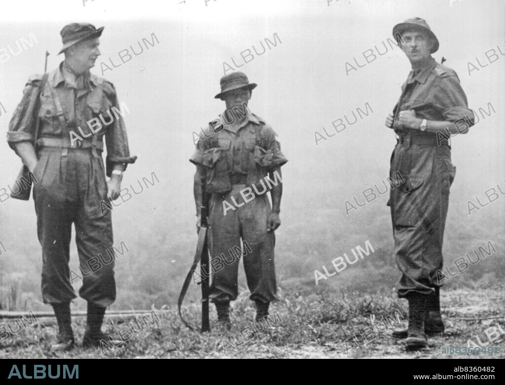 High Com. On Patrol -- General Sir Gerald Templer (right), British high Commissioner in Malaya, hooks his thumbs into the pockets of his Jungle-Green Battle-Dress before dropping down into the Mist-Filled valley (background) at the start of a Seven-Mile Jungle Patrol in Negri Sembilan State, Malaya, during the week ending January 31.At left is Major General Sir Hugh Stockwell, General Officer Commanding, Malaya.Both men carry carbines. Between them is a Gurkha member of the Patrol.General Templer spent three days in the jungle to gain first-hand knowledge of operational conditions. February 9, 1953. (Photo by Associated Press Photo).