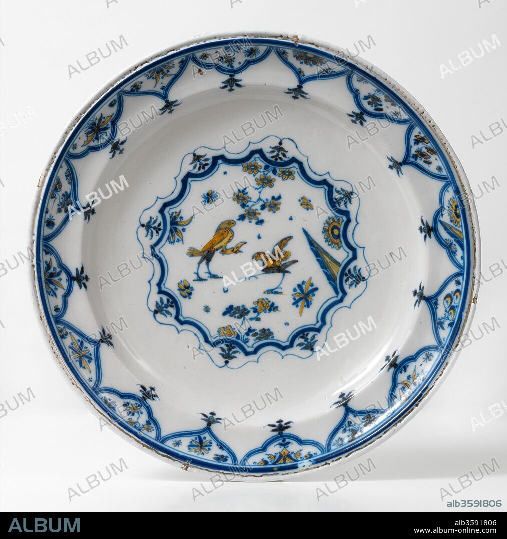 Plato, 1730-1740, Cerámica (Serie de chinescos; loza decorada en azul, verde y amarillo, con dos aves zancudas en un medallón central polilobulado, rodeado de cenefa de motivos ojivales), de manufactura de Alcora (Castellón), Diámetro: 40 cm.
