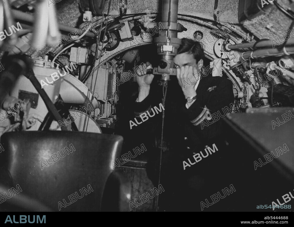 Rare Picture Inside a British Midget Sub -- One of the few pictures ever made inside a midget submarine - Lieutenant Hugh T. Verry, of East Sheen, operates he periscope of his command, the XE 8, in the pool of London today (Wednesday). The midget sub., one of the smallest offensive naval units in the world, is just back from Exercise Mainbrace and is paying a four-days informal visit to London, Operational complement of the tiny ship is understood to be four. October 1, 1952. (Photo by Reuterphoto).