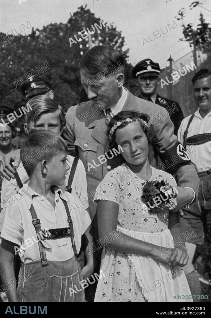 Adolf Hitler with a group of young children, 1936. Baldur von Schirach (1907-1974), the Nazi youth leader, can be seen behind Hitler (1889-1945) in the background. A print from Adolf Hitler. Bilder aus dem Leben des Führers, Hamburg: Cigaretten/Bilderdienst Hamburg/Bahrenfeld, 1936.