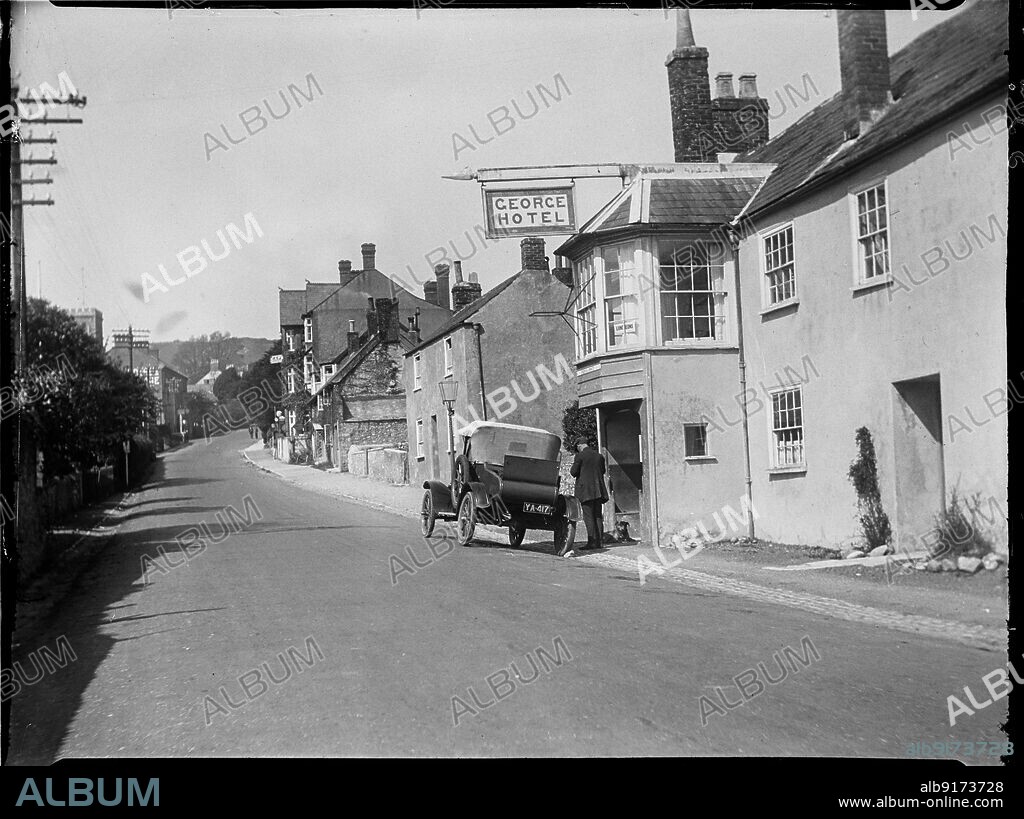 KATHERINE JEAN MACFEE. George Hotel, The Street, Charmouth, West Dorset, Dorset, 1925. A view looking west along The Street with the George Hotel in the foreground, showing a motor car parked outside with a man and dog beside the entrance to the hotel.