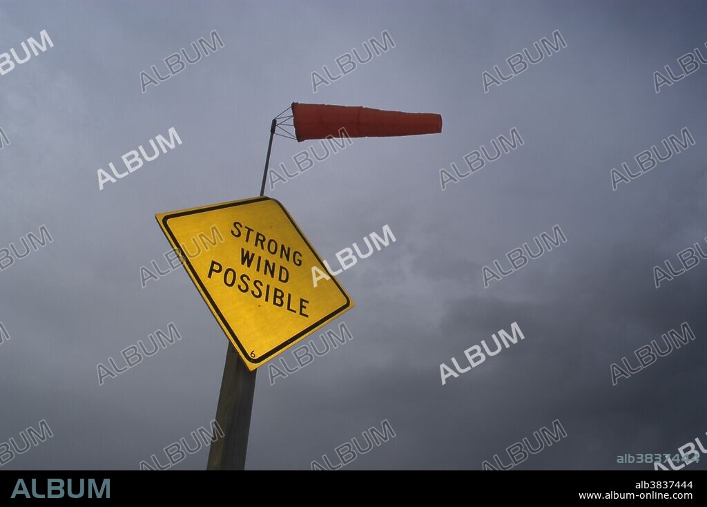 'Strong Wind Possible' sign beneath a stormy sky in Wyoming showing windsock in strong winds.
