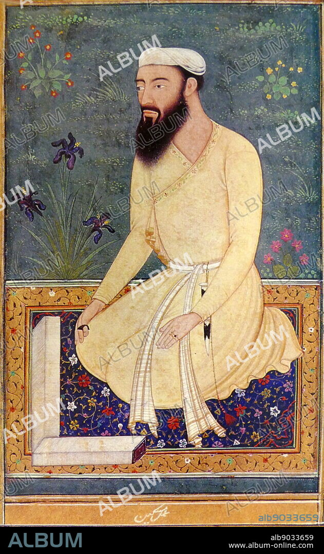 Portrait of a learned Mughal courtier. He is kneeling on a richly coloured carpet with the pages of unbound book spread out before him; he has a full black beard and moustache and is dressed in a simple white turban and plain yellow jama; a black thumb-ring adorns his right hand; a dagger hangs with a tassel from his sash; irises and other flowers grown in the green grass in the background. Dated 17th Century.