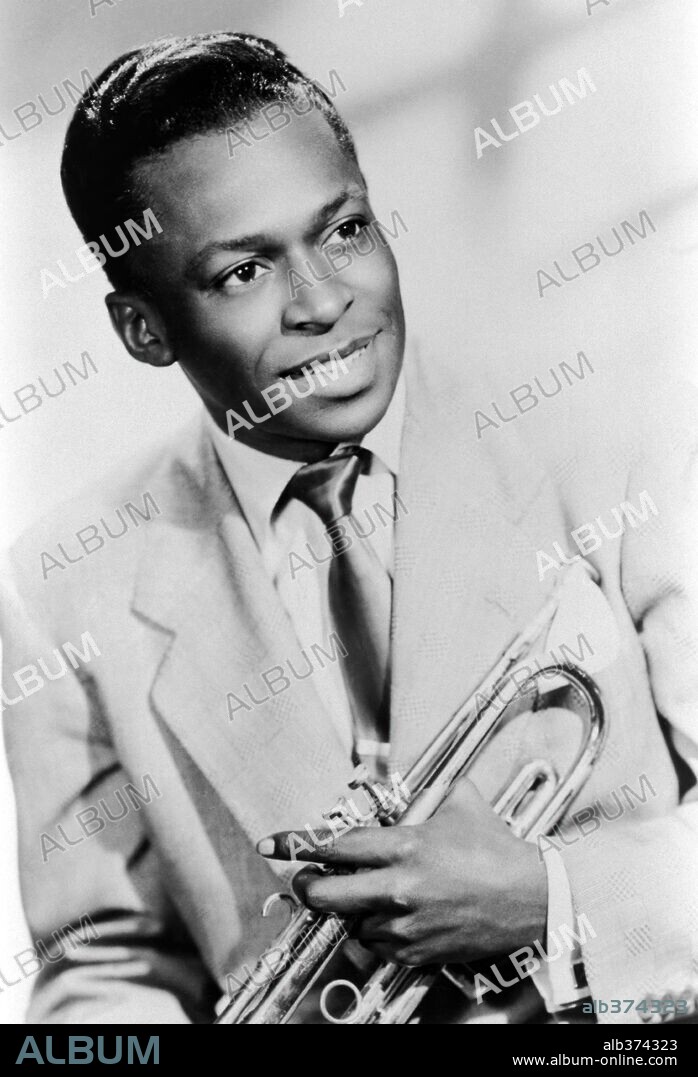 Studio portrait of American jazz trumpeter Miles Davis smiling and holding his trumpet, 1949.