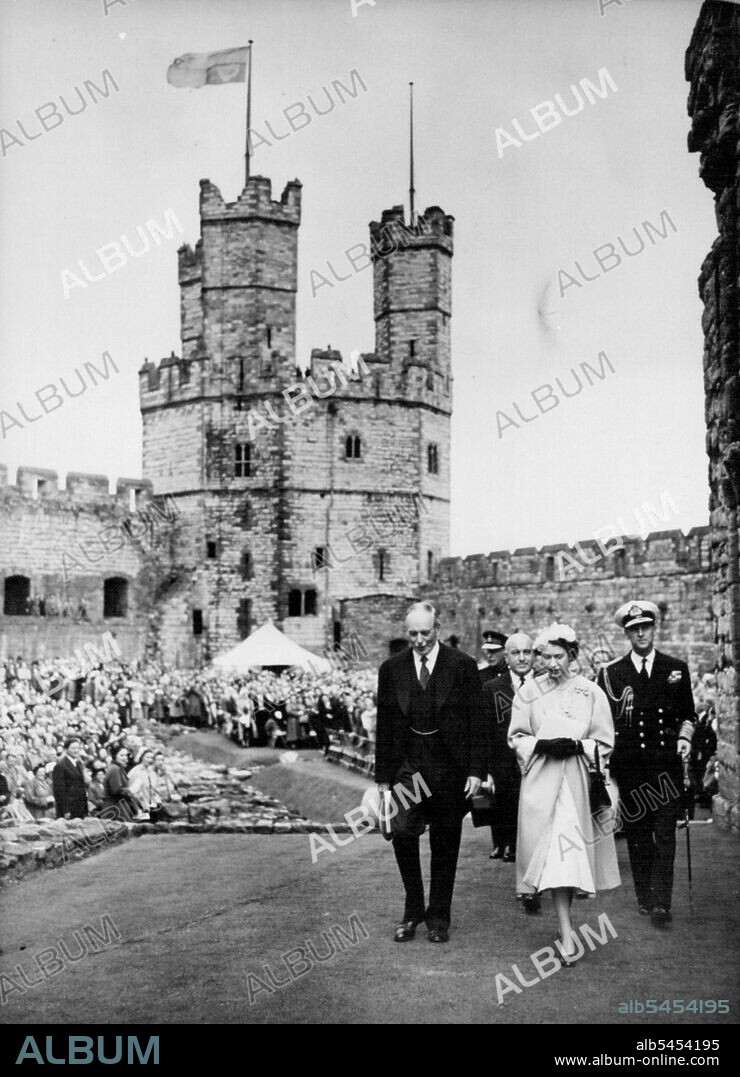 Queen And Duke Visit Caernarvon Castle -- Queen Elizabeth II and the Duke of Edinburgh (right), accompanied by Lord Harlech, constable of caernarvon castle (left), are followed by Sir David Maxwell Fyfe, the Home secretary as they walk through the grounds of the castle, July 10th. The royal standard flies from tower of castle. Forty thousand people roared a welcome to the Queen when she visited ancient Caernarvon Castle today July 10th - the first Queen regnant to enter the Welsh stronghold since King Edward I built it seven centuries ago. On a balcony above Queen Eleanor's gate the Queen came out alone to acknowledge the cheers. It was from this gate 700 years ago that King Edward I held up his baby son, the first Prince of Wales, to the Welsh Chieftains. With the cry: "Eich Dyn" - "Your Man". July 12, 1953. (Photo by Associated Press Photo).