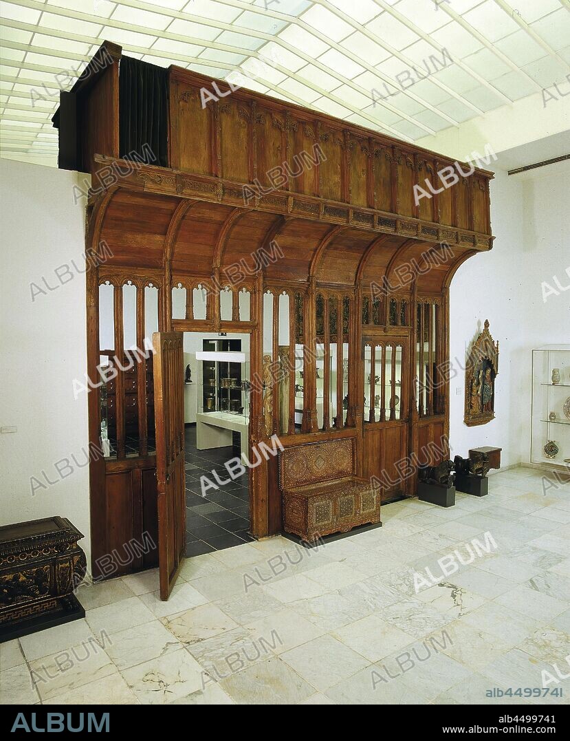 Oksaal (choir separation), from the church in Helvoirt, Oksaal from oak. On a rack of heavy pillars and sills (ribwood) stands a double cove, on which the floor of the actual singer's stand rests. The latter is surrounded on all sides by a bulkhead. The substructure is sealed to breast height with smooth panels, above which are heavy sills. On these deck beams there is a fence of narrow posts that closes against the upper threshold of the substructure in gothic arcades with tracing. Two compartments of the substructure run like doors, but their window sills lie under the upper sill of the whole. In the continuation of the styles of the substructure, the legs of the double cove rise. The counter of the singer's stand is divided on one long side (facing the church nave) by pinnacles into ten panels decorated with Tudor arches and five by five on either side of one built in three sides of the hexagon bay window. The arches are filled in the corner with openwork Gothic traces. The bay window has a free-hanging drip vault below. A powerfully profiled frame separates counter and coffin. At the bottom of this list is a frieze with superimposed openwork vines, alternated by the drippers, into which the pinnacles of the counter end. A low console develops in the middle of each panel from the pedestal of the grandstand, on which saint figures stood. The other long side of the tribune shot has no bay window and is generally treated more simply. There are gothic arched flat arches between the pinnacles. The narrow sides are partially treated as the front. The doors turn on heavy handles. All styles and sills are gathered with 'fish beak'., Ornament, tracery, Helvoirt, anonymous, Netherlands, c. 1500, wood (plant material), oak (wood), h 498 cm × w 563 cm.