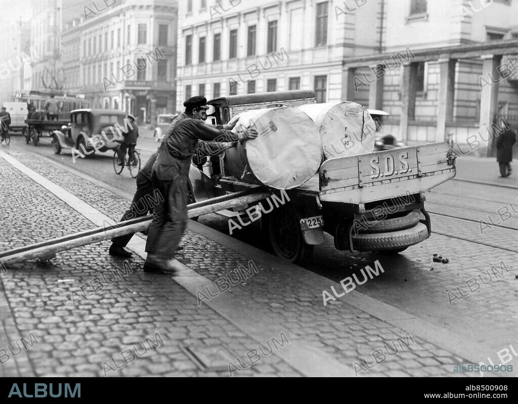 Malmö 19300901. Papper, pappersrullar lossas, lastas av lastbil utanför Sydsvenskan på Östergatan 30 i. Malmö för att vinschas ner i källaren där rotationstryckeriet var beläget. Troligen 1930. Foto okänd / Sydsvenskan / SCANPIX. **OUT Kvällsposten, Skånska Dagbladet, Metro Skåne**. ***BETALBILD***.