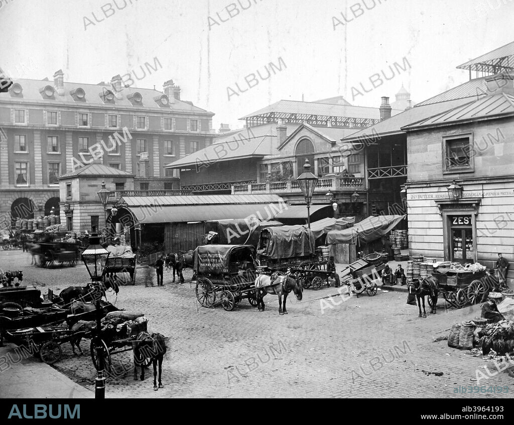 Covent Garden, Westminster, London. Covent Garden Market, London's fruit market, as roofed in 1874-5 by William Cubitt. Bedford Chambers, built in 1877-9 by H Clutton, is visible to the north. In the foreground, among other horsecarts, is a cart belonging to Carter Paterson.