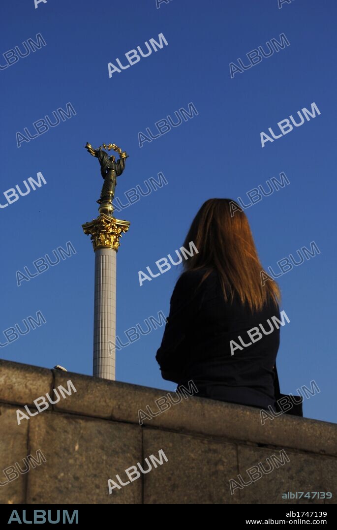 UCRANIA. KIEV (KYIV). Capital de la ciudad. Mujer contemplando la estatua de la Madre de Ucrania, en lo alto de la Columma de la Independiencia, ubicada en el centro de la céntrica Plaza de la Independencia (Maidan Nesaleshnosti). Europa oriental.