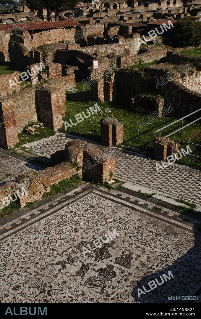 ARTE ROMANO. ITALIA. CASA DE BACO. "Domus" romana construida en época adriana. Siglos I-II d. C., según la técnica (Opus mixtum). Vista general, donde destaca el MOSAICO en blanco y negro decorado con motivos florales. En el panel central, las figuras de BACO (dios del vino) JUNTO A SU MUJER ARIADNA. En la fila inferior, la lucha de EROS Y PAN (el amor y la lujúria). Un viejo sileno media como árbitro. Antigua ciudad romana de OSTIA ANTICA. Alrededores Roma. Italia. Europa.