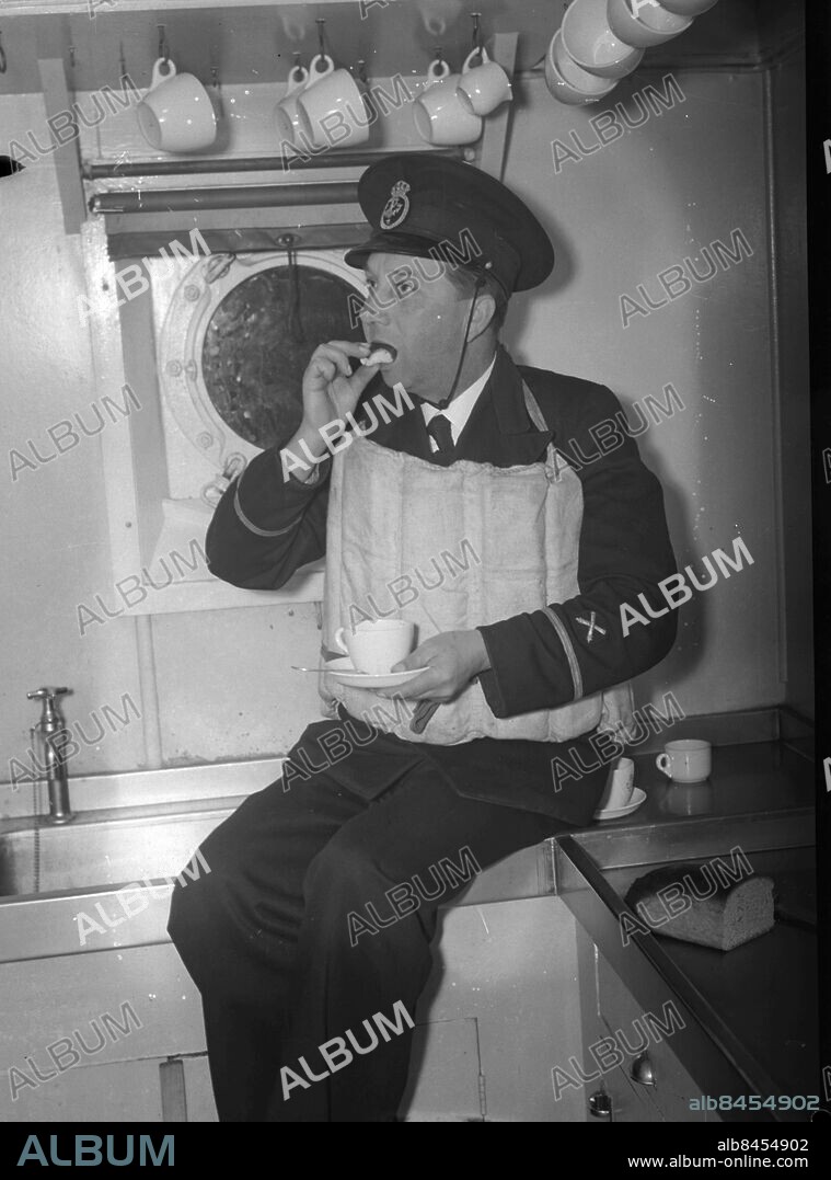 GÖTEBORG 1943-04-21.. Letandet efter ubåten Ulven som sjönk vid Stora Pölsan utanför Göteborg. Ett befäl tar rast i kabyssen - det blir en smörgås och en kopp kaffe. *** Local Caption *** GT Låda 1943-mars-april-maj-jun-jul-aug- Foto: Kamerareportage / TT / Kod: 2524.
