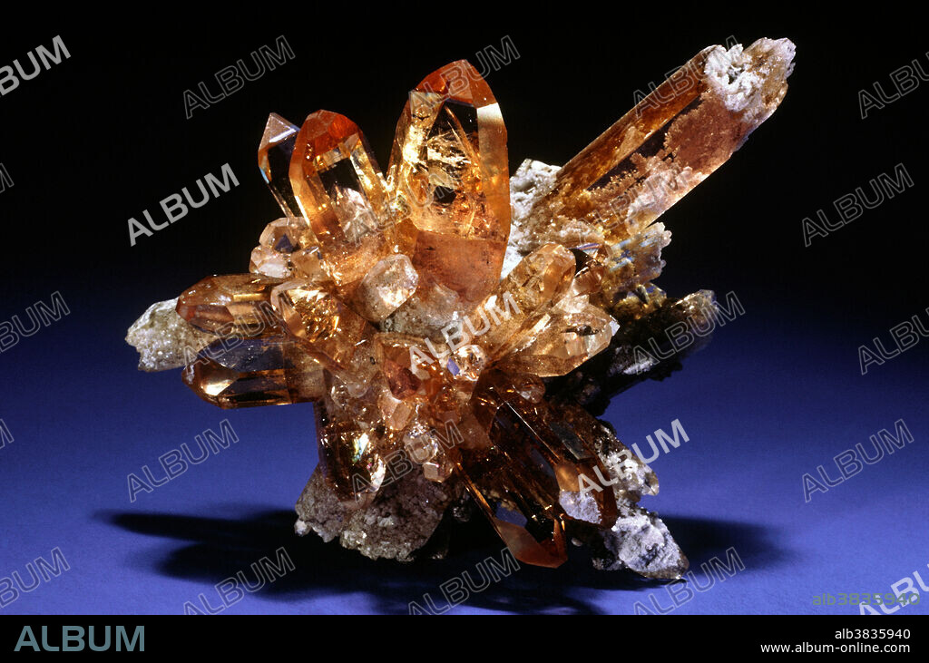Topaz is aluminum fluosilicate, and is common and abundant in many parts of the world. It occurs worldwide as fine crystals, often transparent, some weighing as much as 100 kilograms, and is found in a wide variety of colors. Crystals are often incredibly sharp and well formed. Topaz is also an important gemstone and represents the month of November. Precious topaz is orange material from Brazil; Imperial topaz is reddish-orange, red or pinkish-orange in hue. Blue topaz is produced in huge quantities by heating colorless topaz that has been turned brown by irradiation. Fine 'sherry colored' topaz crystals occur in sprays in the volcanic rocks of the Thomas Range, Utah.