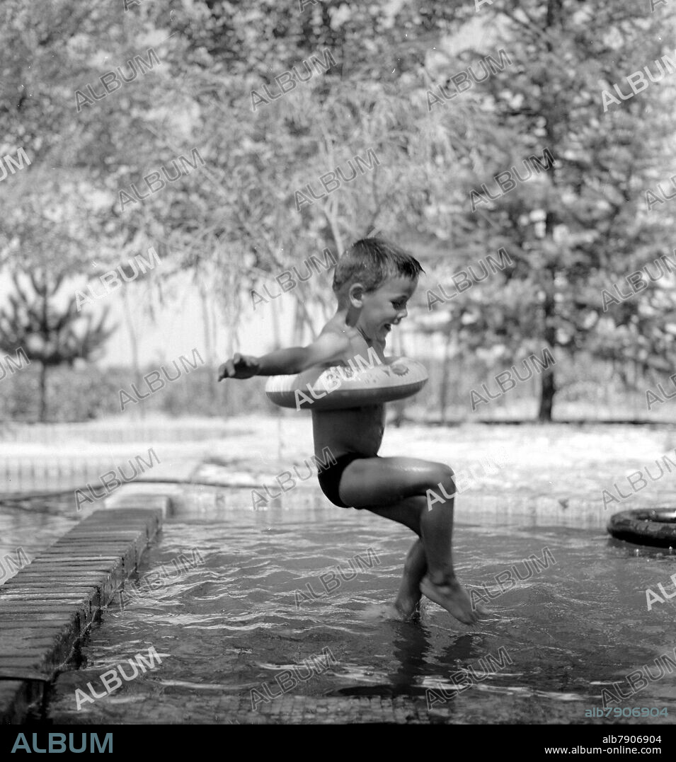 NIÑO SALTANDO A UNA PISCINA CON FLOTADOR - FOTOGRAFIA EN BLANCO Y NEGRO - AÑOS 60 -.