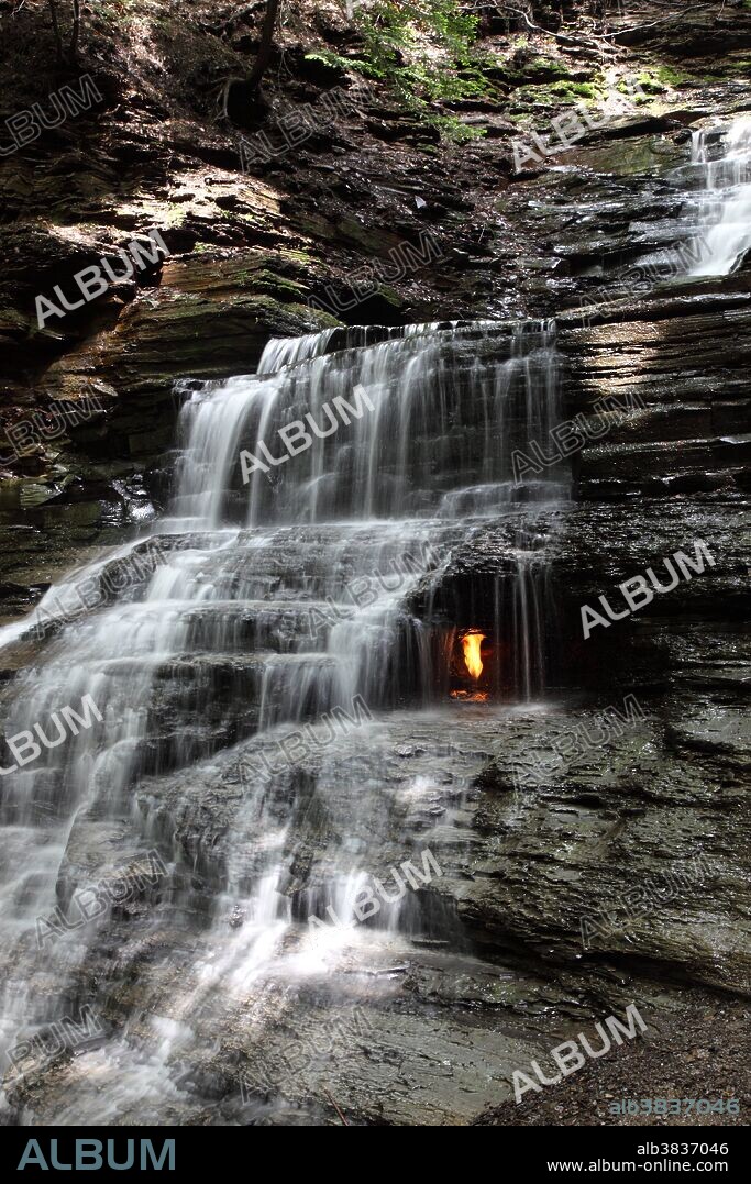 Eternal Flame Falls is in Chestnut Ridge Park located near Orchard Park New York. This 10 meter waterfall cuts through a layer of Hanover Shale of the Late Devonian Epoch that is 85 to 95-feet thick. This shale is greenish-gray to gray colored with some black bands. Natural gas leaks from a seam in the rocks under the waterfall. This natural gas deposit can be easily found by its strong smell of hydrogen sulfide or the smell of rotten eggs. When the flame it lit the smell substantially subsides. Methane is a gas at room temperature and pressure, and the main component of natural gas.