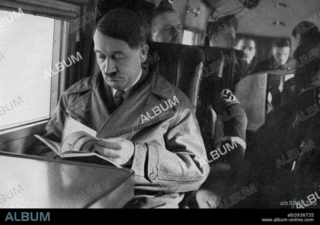 Adolf Hitler on an aeroplane, 1936. Hitler (1889-1945) reading a book during a flight. A print from Adolf Hitler. Bilder aus dem Leben des Führers, Hamburg: Cigaretten/Bilderdienst Hamburg/Bahrenfeld, 1936.