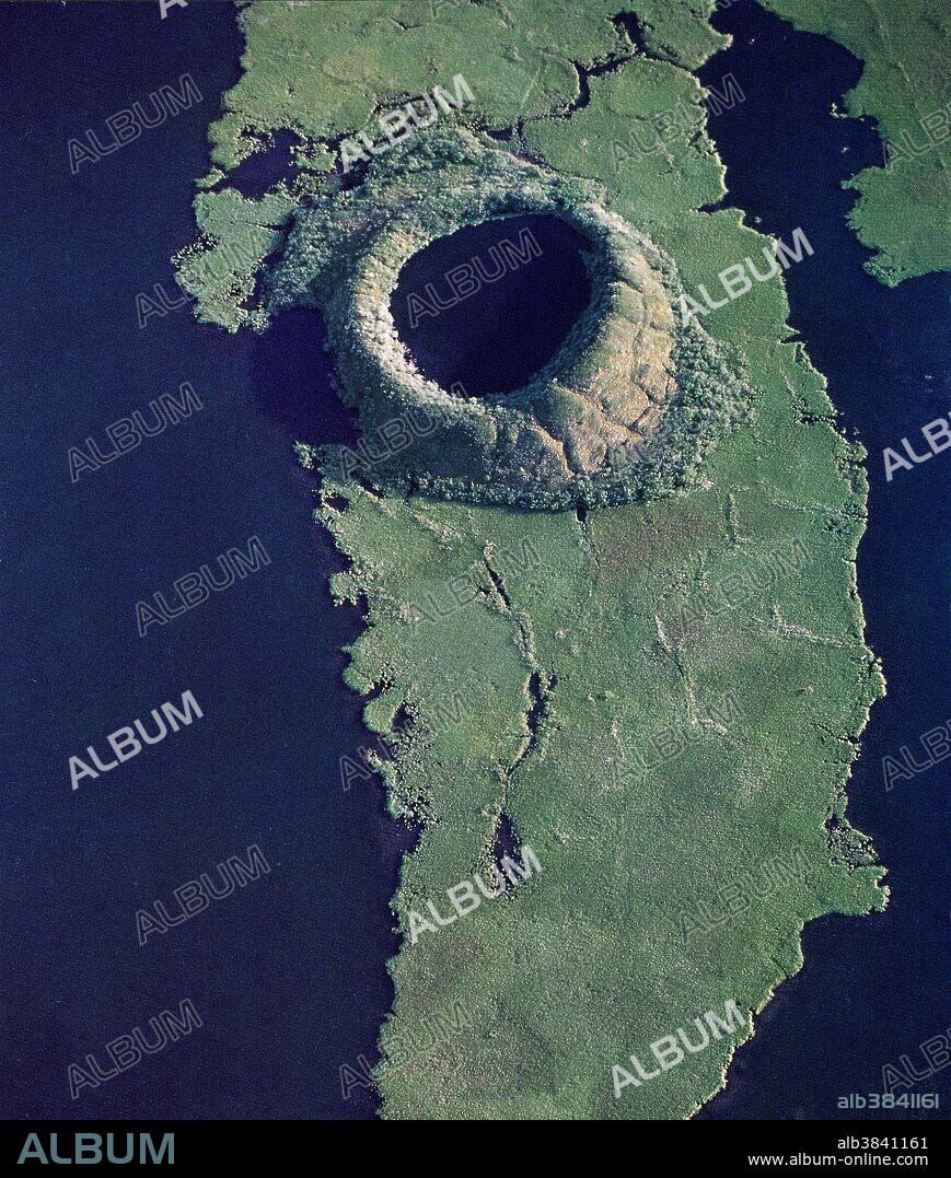 Collapsed pingo on the Tuktoyaktuk Peninsula in Canada. Unfrozen underground areas are sometimes engulfed by permafrost, causing that area to freeze. As it does, the pressure exerted by the expanding ice forces earth upward, forming a dome shape on the surface. This is called a pingo. Sometimes the surface of the dome cracks, exposing the underlying ice and allowing that ice to melt, which causes the dome to collapse. This is the process that has formed the topography in this image.