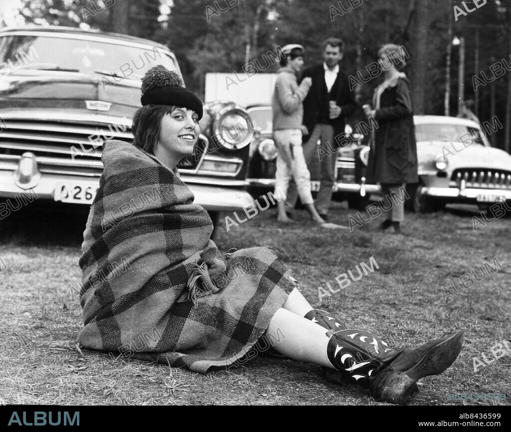 ARKIV 1962 - I anslutningen till Velodromloppet invaderas Karlskoga av raggare. En "raggarbrud" sitter invirad i en filt, iklädd texasstövlar mitt på raggarnas parkeringsplats. Foto: TT Kod: 190 COPYRIGHT SCANPIX SWEDEN.