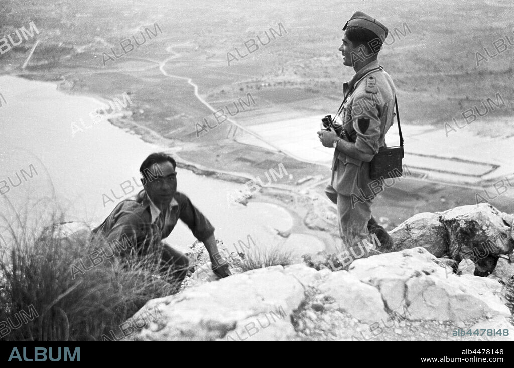 España. Guerra civil (1936-1939). Falange española y de las J.O.N.S. División 72 del Cuerpo del Ejército de Castilla. Flechas Verdes, junto a legionarios del Corpo Truppe Volontaire, CTV, formaron una unidad mixta italo-española movilizada para hacer frente en la ofensiva de Catalunya al final de la contienda. Oficial italiano y un soldado en el peñón de Ifach, en Calpe, observando el mar y las salinas a través de unos prismáticos. Marzo de 1939.