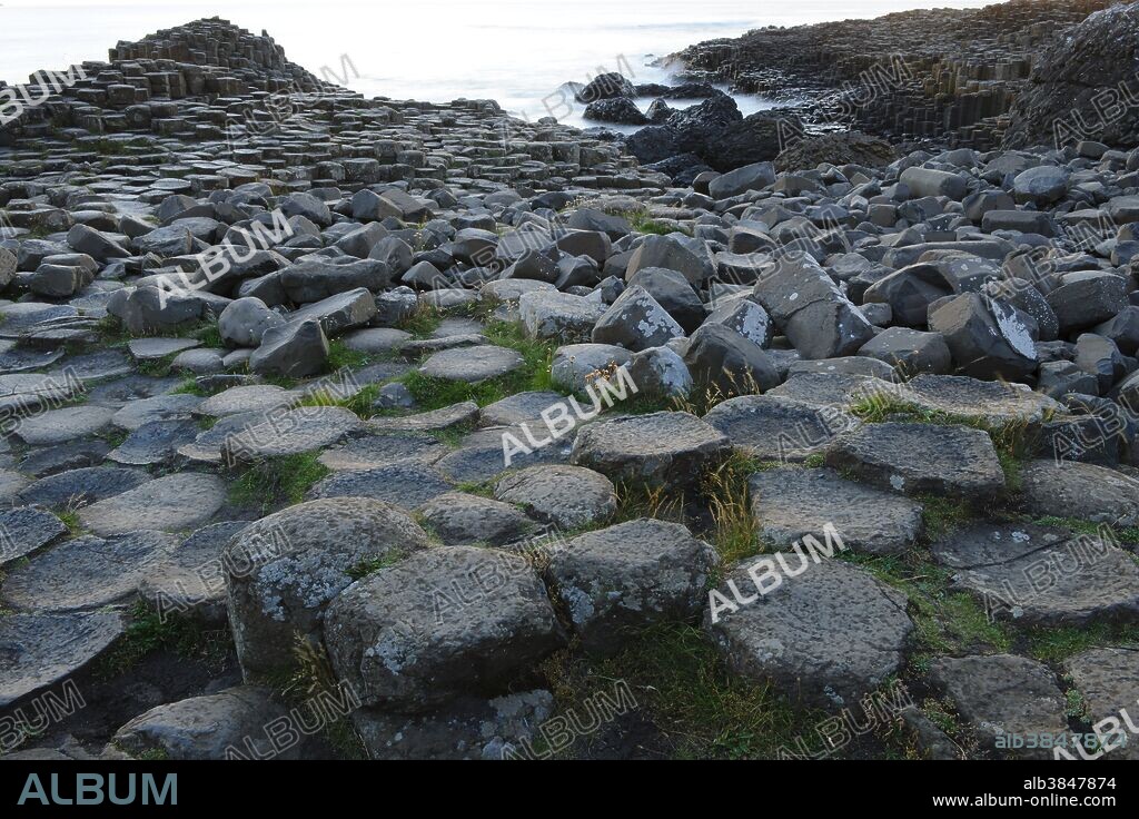 The Giant's Causeway, County Antrim, Northern Ireland. The Giant's Causeway, a UNESCO World Heritage Site, is an area of interlocking basalt columns on the northeast coast of Northern Ireland. It is the result of an ancient volcanic eruption. The tops of the columns form stepping stones that lead from the cliff foot and disappear into the sea.