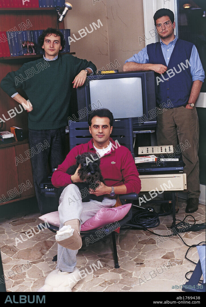 Gialappa's Band members posing together. Carlo Taranto and Giorgio Gherarducci with Marco Santin, sat with a foot in plaster and a dog in his arms. 1992.