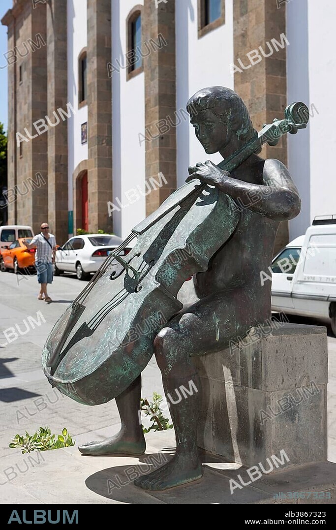 Village square with a bronze sculpture of a cello player, Homenaje a la Musica by A L Benitez in the historic centre of Agueimes, Gran Canaria, Canary Islands, Spain, Europe.