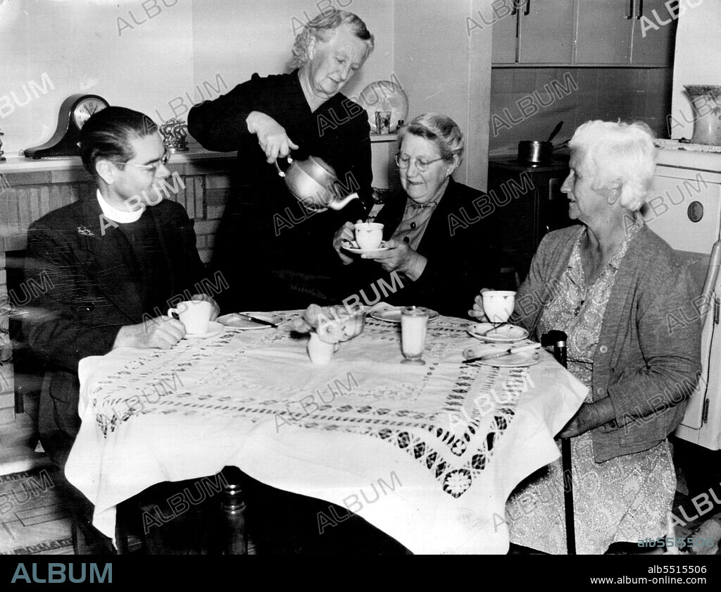 Hammondville's director the Rev. Bernard Judd enjoys a cup of tea with Mrs. Daniel Lane, Mrs. C. Wright, and Mrs. James Gilman in Mrs. Lane's living room on one of his bi-weekly visits to the village. February 01, 1955.