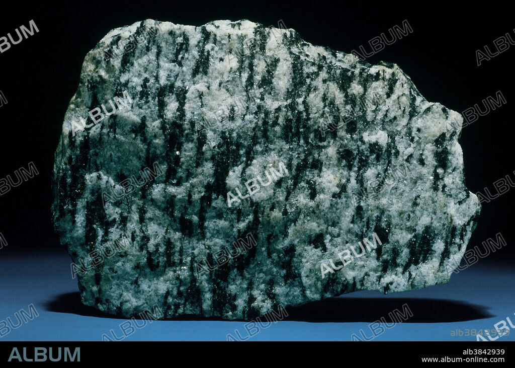 Gneiss is a very general term that refers mainly to a rock texture, rather than a specific rock type. Gneissic texture implies streaking or banding, a lineation in the components of a rock, as opposed to the layering or stratification in sedimentary rocks. Gneiss may therefore be igneous or metamorphic in origin. Gneiss generally contains feldspar, and typically has alternating bands of rounded and flattened mineral grains. The biotite gneiss from Uxbridge, Massachusetts is a good example, where plates of black biotite mica alternate with bands of feldspar and quartz.