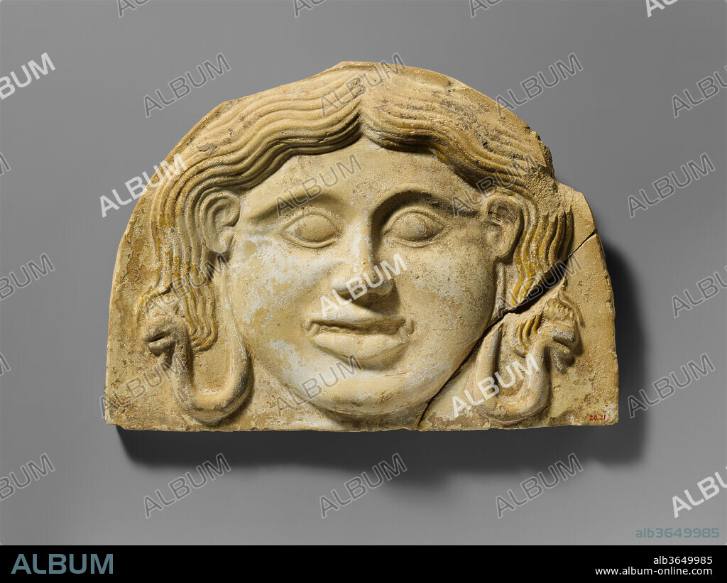 Terracotta gorgoneion antefix (roof tile). Culture: Greek, South Italian, Tarentine. Dimensions: H. 7 5/8 in. (19.4 cm.)
W. 10 3/4 in. (27.3 cm.). Date: 2nd half of the 5th century B.C..
The style of this gorgoneion antefix is of a transitional type between the archaic, more fierce Medusa and the calm Medusa of later centuries. Traces of white slip remain on her face, and a few traces of paint from the once bright yellow hair can still be seen on her head. The irises of her eyes would have been painted blue or black.