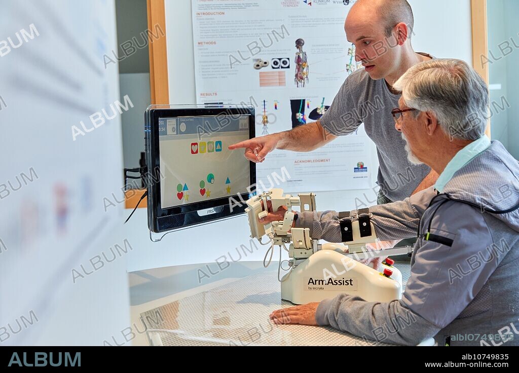 Patient with assistive robot for upper limb rehabilitation, The robot ArmAssist allows passive, assisted and active training of the arm and hand, allowing the treatment of most of the stroke patients. Medical device for neurological treatment.The software platform allows remote patient progress assessment and management of the therapy based on serious games, which motivate patients to actively participate in their rehabilitation and maximize the outcome, Lab Home, Unit of Health Technology, Technology Centre, Tecnalia Research & Innovation, Donostia, San Sebastian, Gipuzkoa, Basque Country, Spain.