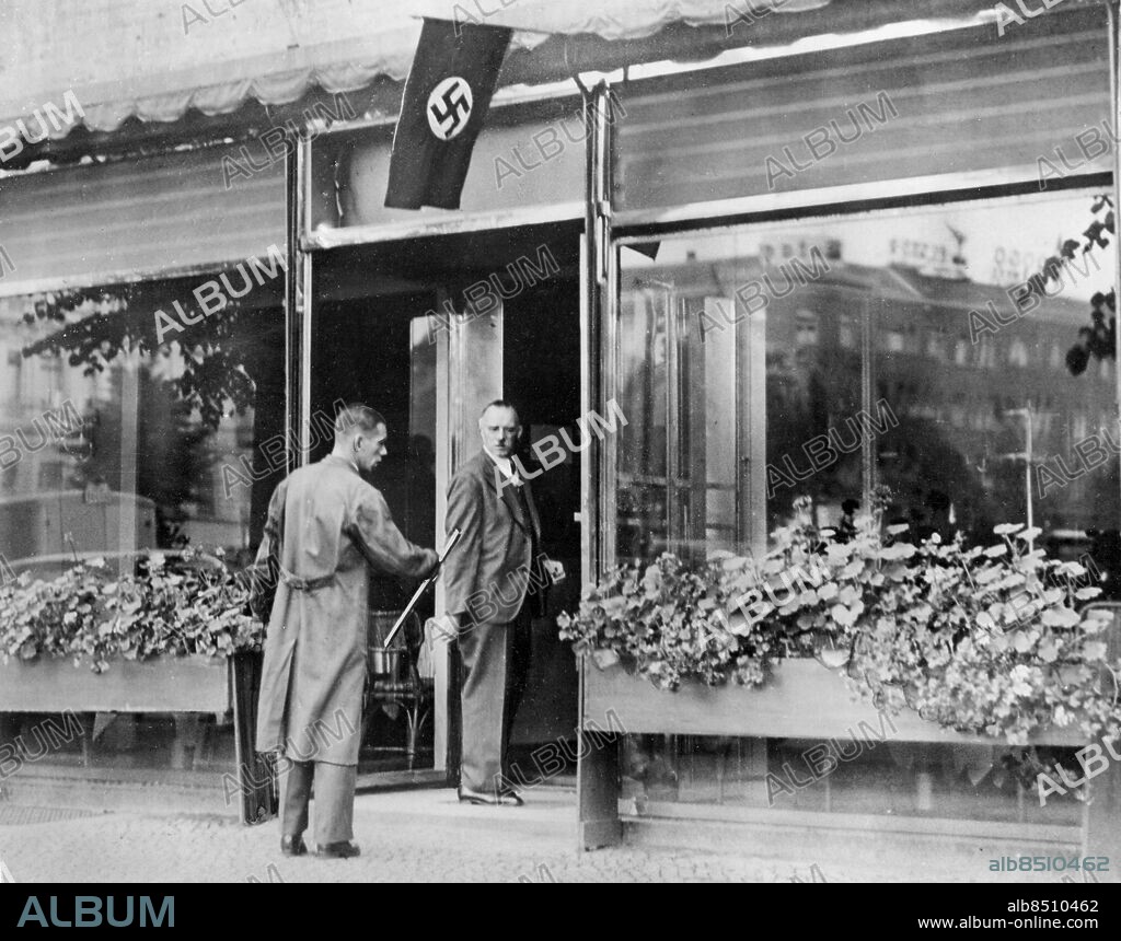 Orig. bildtext... HITLER'S BROTHER ALOIS EXTENDS INN BUSINESS. 27.8.37. Herr Alois Hitler, Chancellor Adolf Hitler's oldest half-brother, who keeps a small inn in a Berlin suburb, is branching out in a big way in Berlin's fashionable West End; he is opening a new Kurfurstendamm cafe-restaurant. Herr Alois has been making a steady profit from his inn since his brother came to power. O.P.S. Herr Alois Hitler talking to the architect outsidehis new cafe in Berlin. Not. Hitler, Alois Anm. Alois Hitler, Jr., 1882-1956, tysk kafe- och restaurangägare, halvbror till Adolf Hitler. Hakkors CD568 persons: ALOIS HITLER sites: BERLIN;TYSKLAND.