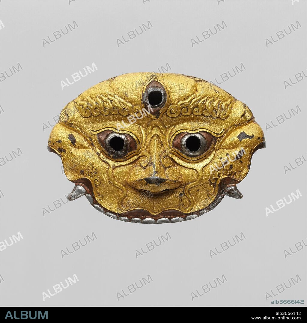 Sword Guard. Culture: Tibetan or Chinese. Dimensions: H. 3 1/4 in. (8.3 cm); W. 4 3/4 in. (12.1 cm). Date: 14th-15th century.
Depicting the face of a wrathful Tibetan Buddhist guardian deity, this extremely rare sword guard was originally part of a complete and very lavish sword. It is from the peak period of Tibetan or Sino-Tibetan ironwork, coinciding with the rule of the Phagmodrupa kings in central Tibet and the Hongwu and Yongle dynasties in China. It is exceptional for the precision and crispness of its chiseling, punched work, and damascening; for the height of the raised decoration; and for the balance and cohesion of its overall design.