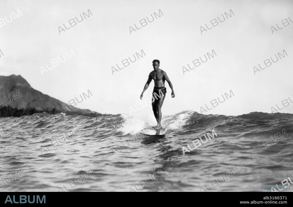 Honolulu, Hawaii: 1929 A man ridng on a surfboard at Waikiki Beach with Diamond Head in the background. He is possibly Duke Kahanamoku.